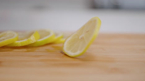 freshly sliced bright yellow lemon coin spinning in slow motion on cutting board in kitchen