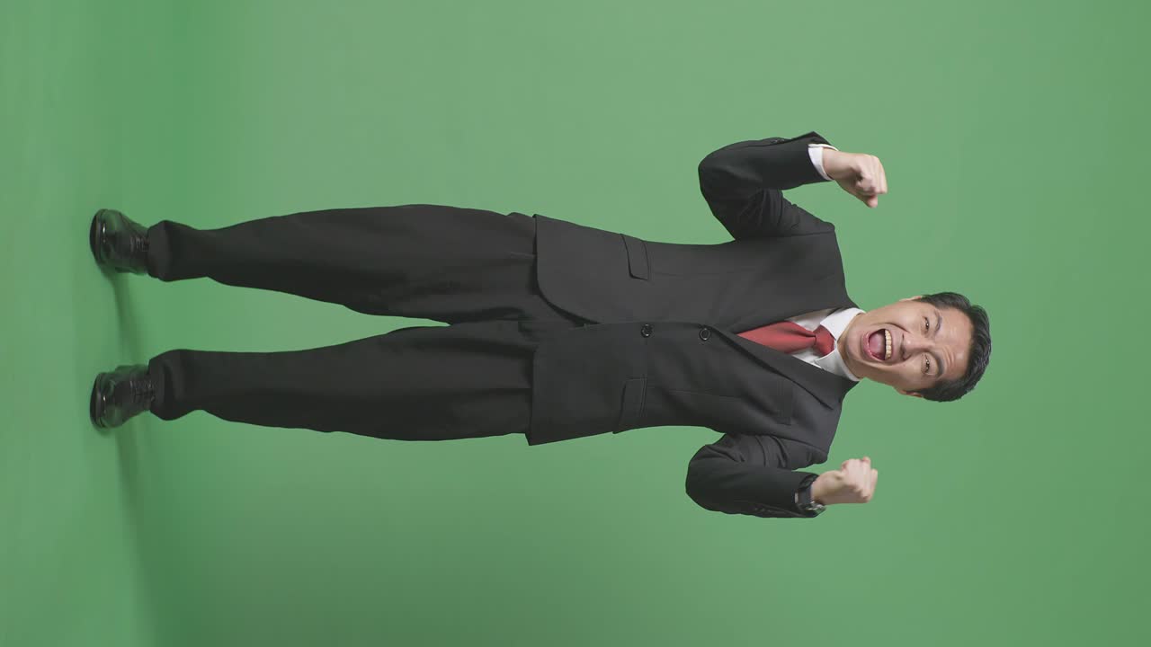 행복한 아시아 사업가의 몸이 가득 차 있습니다. 스튜디오에서 녹색 스크린에 서서 축하하고 있습니다.