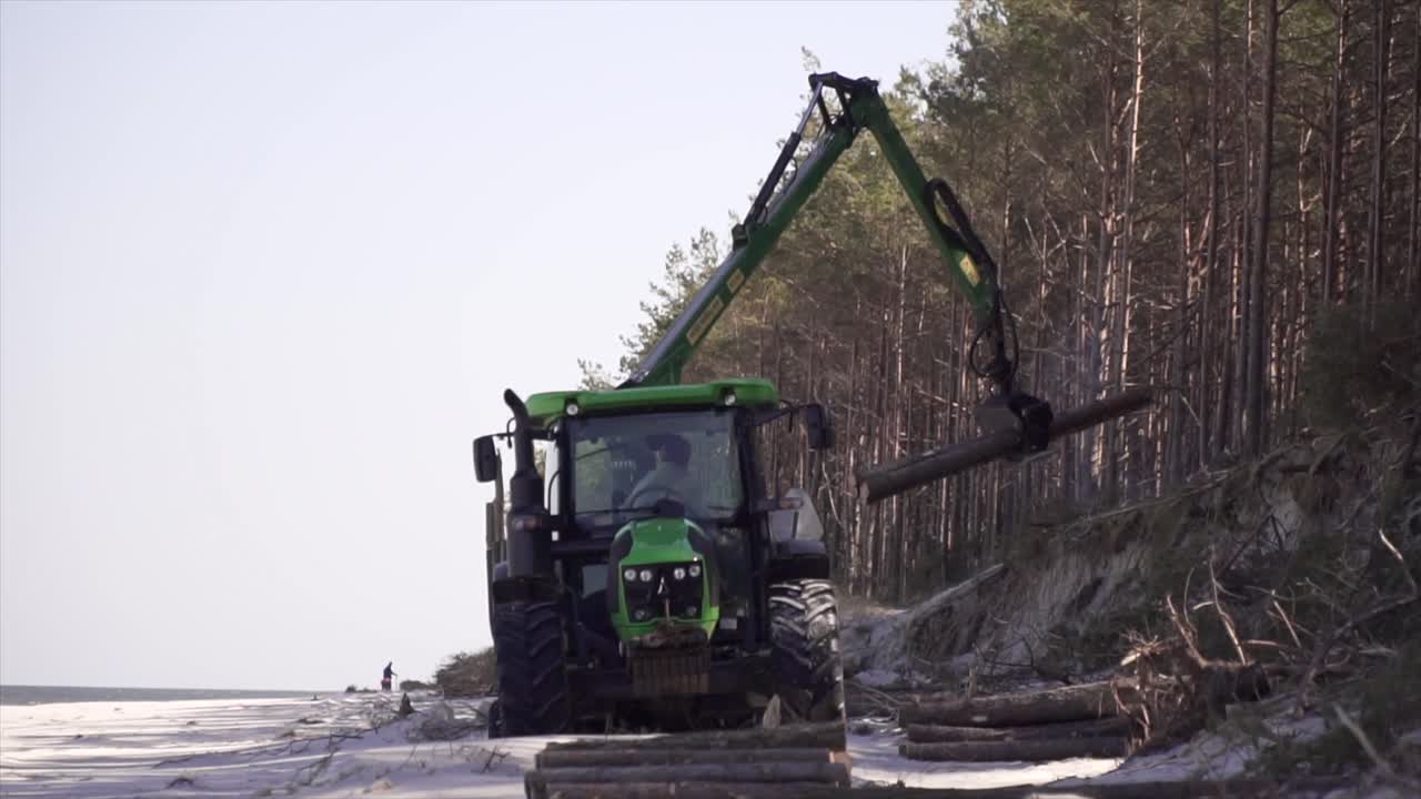 Front view of a tractor loading logs onto a trailer