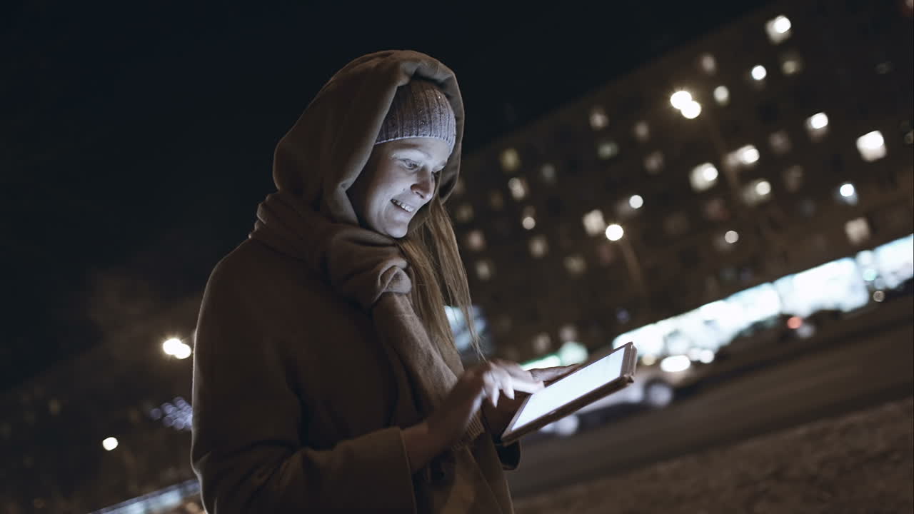 Donna che digita su touchpad mentre cammina in città di notte