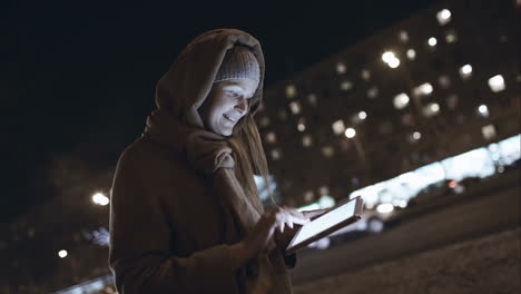 Frau-Mit-Touchpad-Tippt-Unterwegs-In-Der-Nächtlichen-Stadt