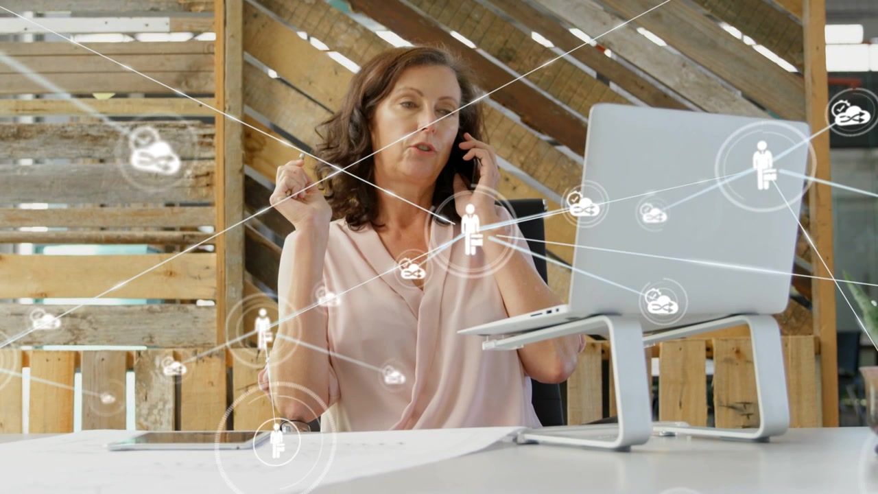 Donna che parla al telefono mentre uno sguardo al laptop attiva l'espansione di icone di rete, visualizzando il lavoro di squadra.