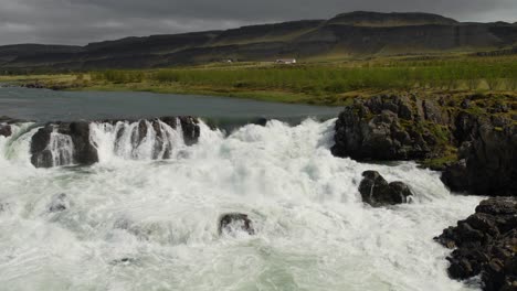 una pequeña cascada en una sección rocosa del río en algún lugar del majestuoso campo islandés