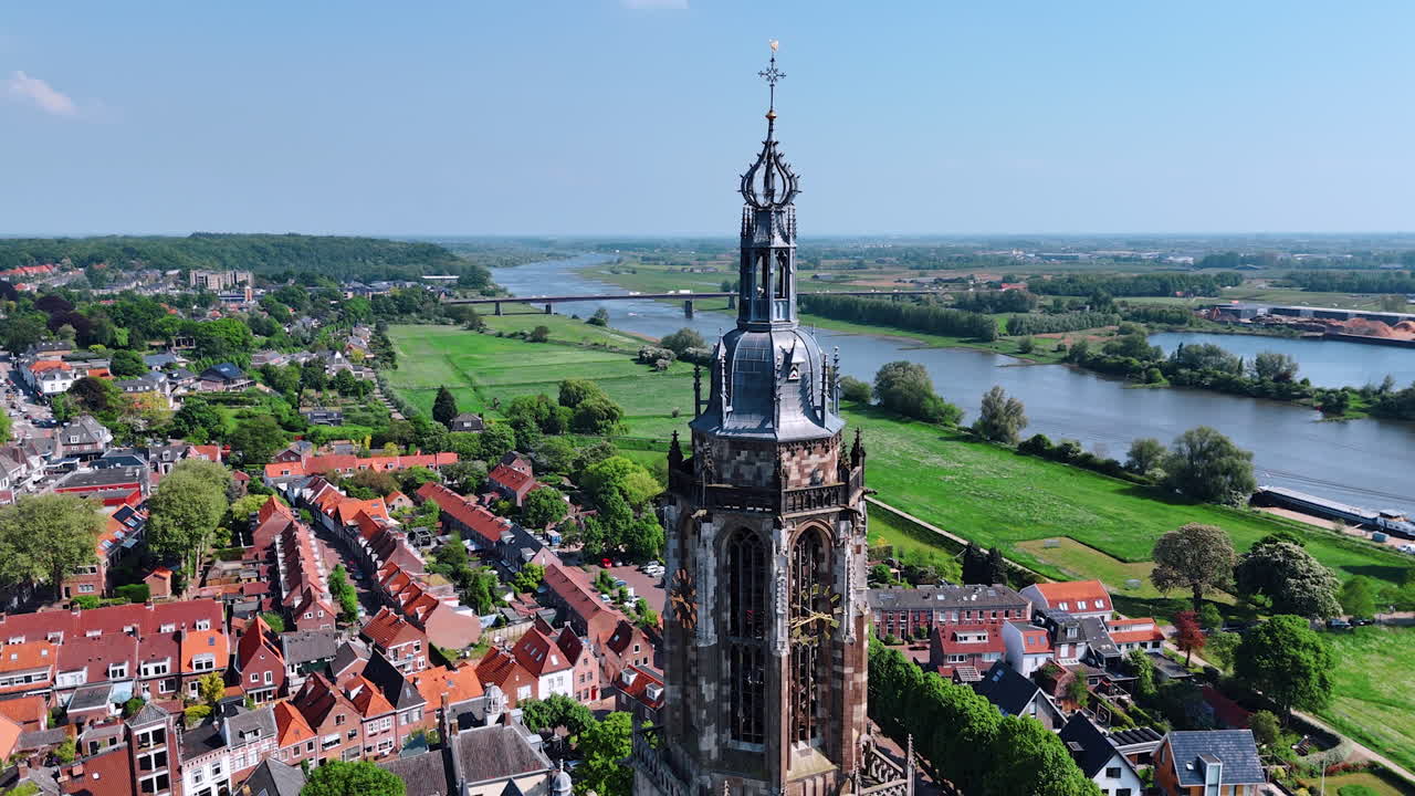 Flying around the top of a beautiful clock tower on sunny day. Cunera Church in Rhenen, Province Utrecht, the Netherlands. Beautiful view on the cozy city from drone.
