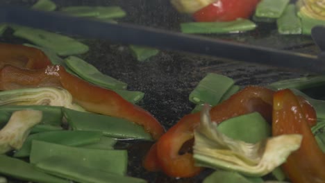 revolviendo verduras frescas en un fuego abierto en un plato de paella