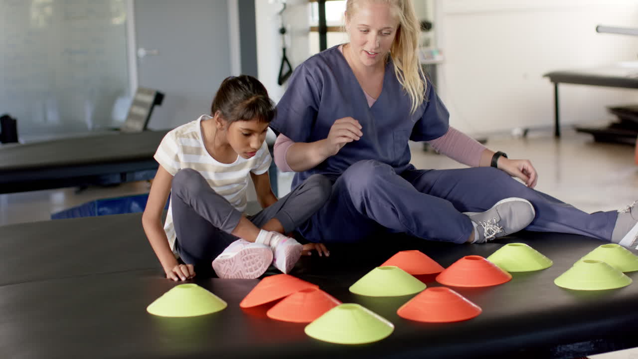 Rehabilitation therapist helping girl with cerebral palsy with disability in physical therapy