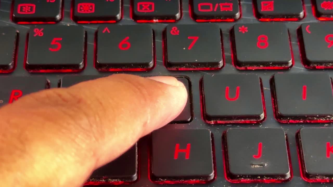 Close-up of hand typing on illuminated keyboard in "y" button, symbolizing internet usage and modern digital lifestyle