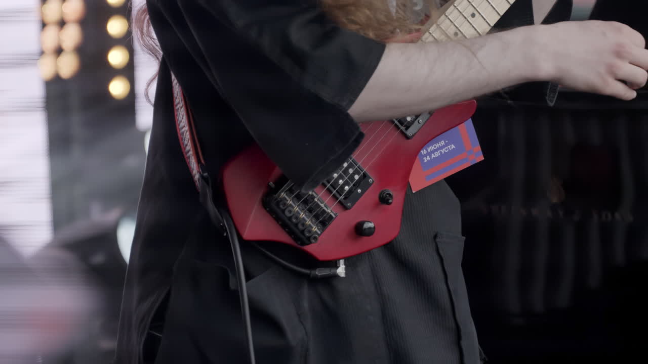Kvinde spiller en lille rød guitar på scene