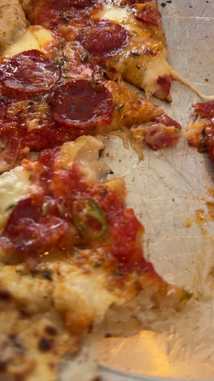 Fette di pizza al salamino piccante parzialmente mangiate su un vassoio di metallo