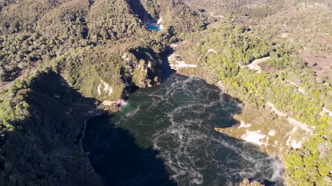 el drone aéreo del valle volcánico de waimangu vuela hacia atrás revelando una toma del lago de sartén y el cráter del infierno, las aguas termales del lago, el lago rotomahana en el fondo
