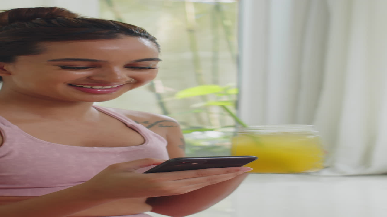 Sportswoman Having Lemon Drink and Checking Smartphone after Home Training