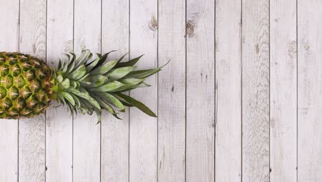 pineapple rolling in place on left side of wooden theme. stop motion