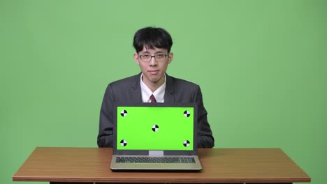 young asian businessman showing laptop to camera