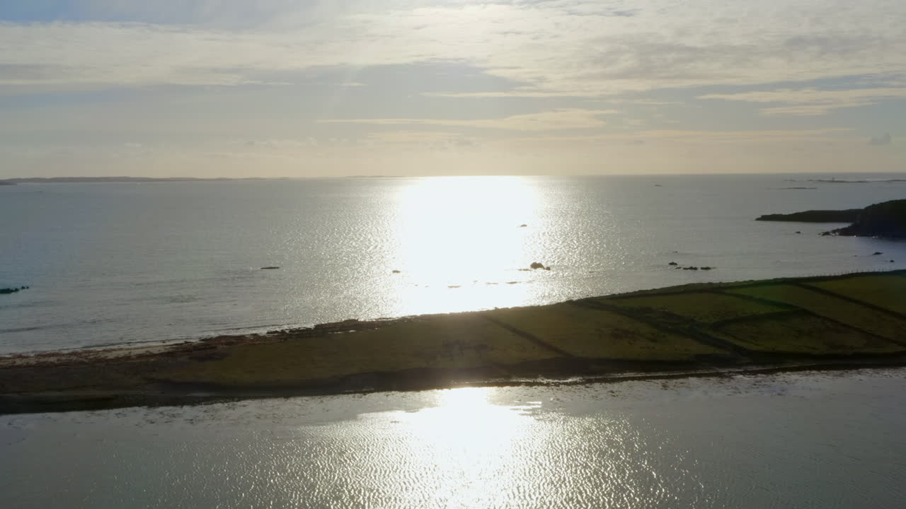 Ascending aerial of Ardmore Island with the sun’s reflection stretching to the horizon.