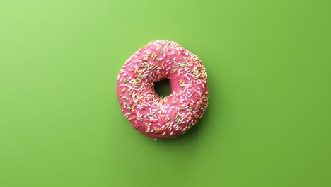 vista superior giratoria rosado vidriado pastel de rosquilla aislado en verde. disparado en el cuervo rojo cámara de cine 4k