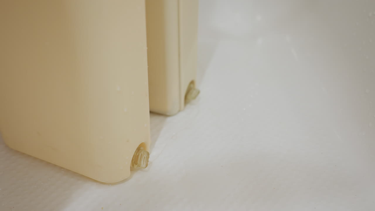 Close up of person hand adjusting shower door seal on wet bathroom floor, focusing on cleaning maintenance and repair detail, ensuring proper sealing to prevent water leakage