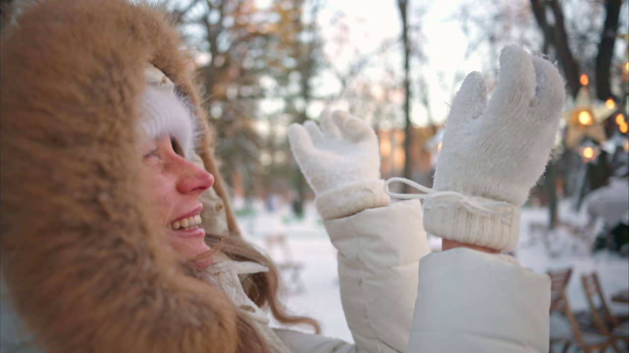 Woman having fun in winter throwing white snow in the air and smiling, slow motion