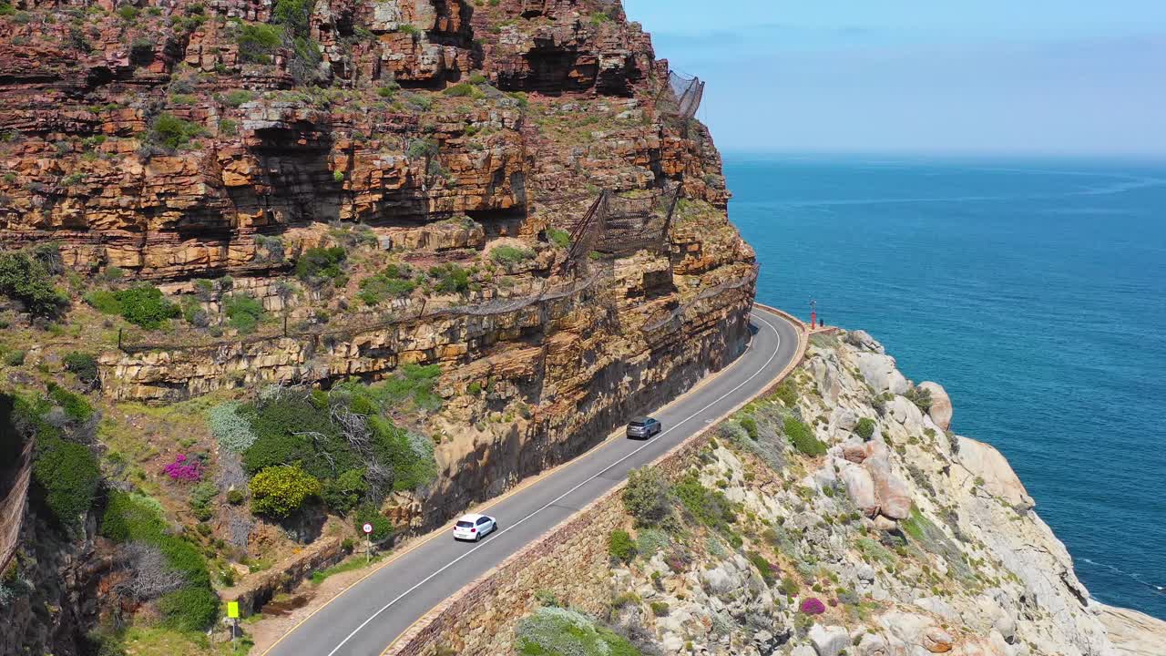 남아프리카 케이프 타운 근처의 바다 채프먼스 피크 도로를 따라 위험한 좁은 산길을 여행하는 자동차의 공중 샷