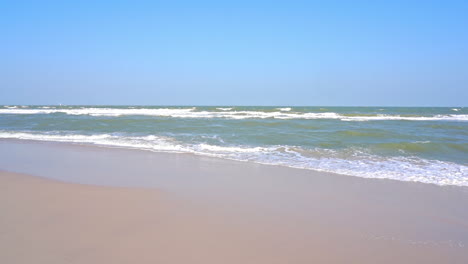 waves slowly wash up on a golden tropical beach