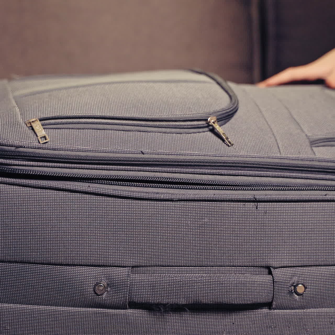 Two cute boys are playing with grey suitcase in the room at home. One little kid is inside the big valise and another boy is closing it.