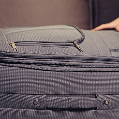 two cute boys are playing with grey suitcase in the room at home. one little kid is inside the big valise and another boy is closing it.
