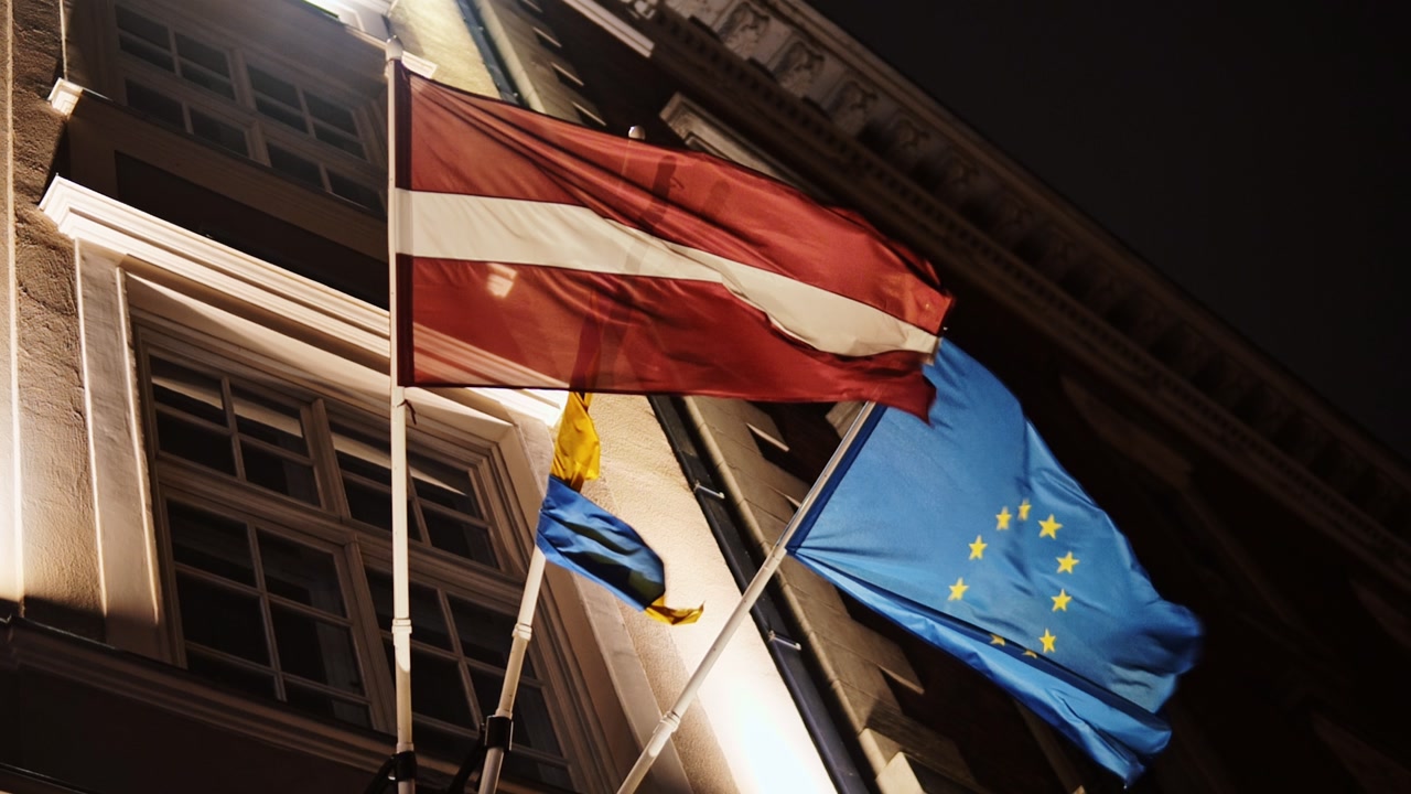 Latvian Ukrainian and EU flags waving gracefully in slow motion on Riga facade
