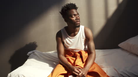 portrait of young black inmate sitting on prison bed