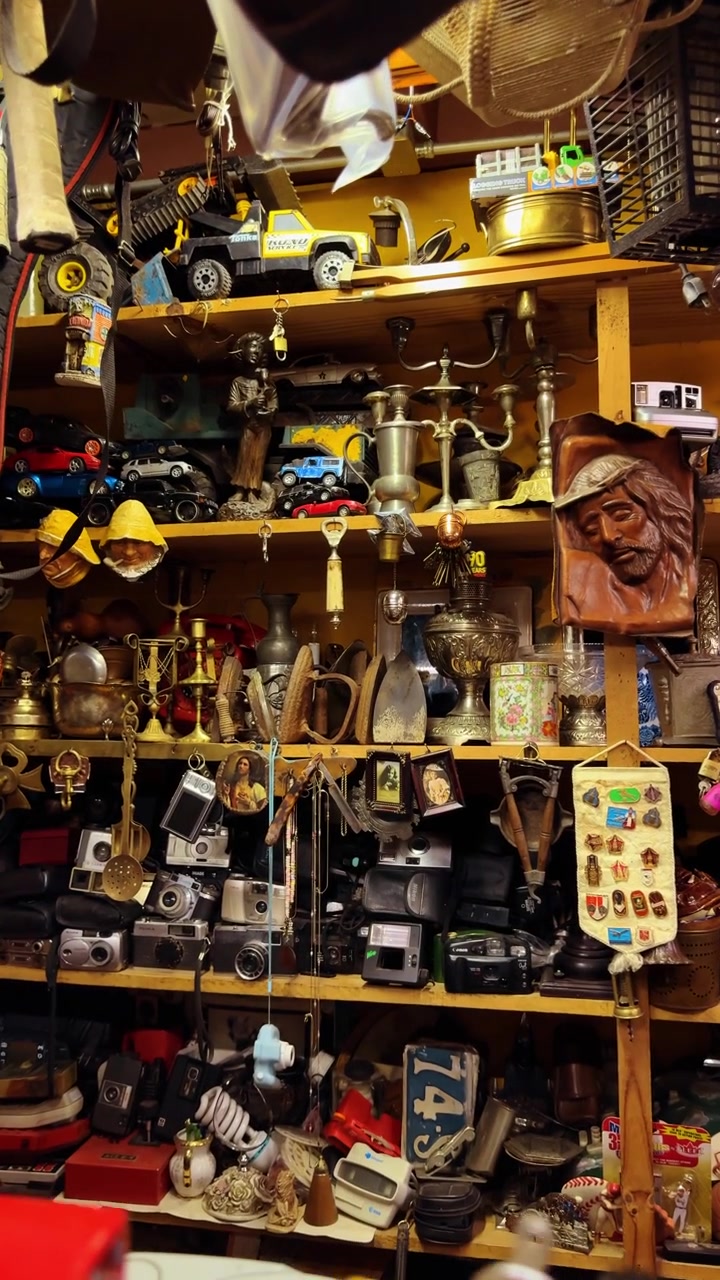 San José, Costa Rica, 7 de agosto de 2025: Colecionáveis vintage em prateleiras de madeira em um mercado de pulgas, Costa Rica. Câmeras, brinquedos, castiçais de latão, esculturas e memorabilia densamente dispostos