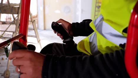 persona que usa los palos de control para perforar el piso dentro de un sitio de construcción mientras que el hombre que usa la excavadora él
