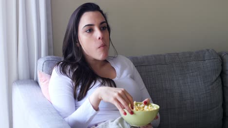 hermosa mujer comiendo palomitas de maíz en el sofá 4k