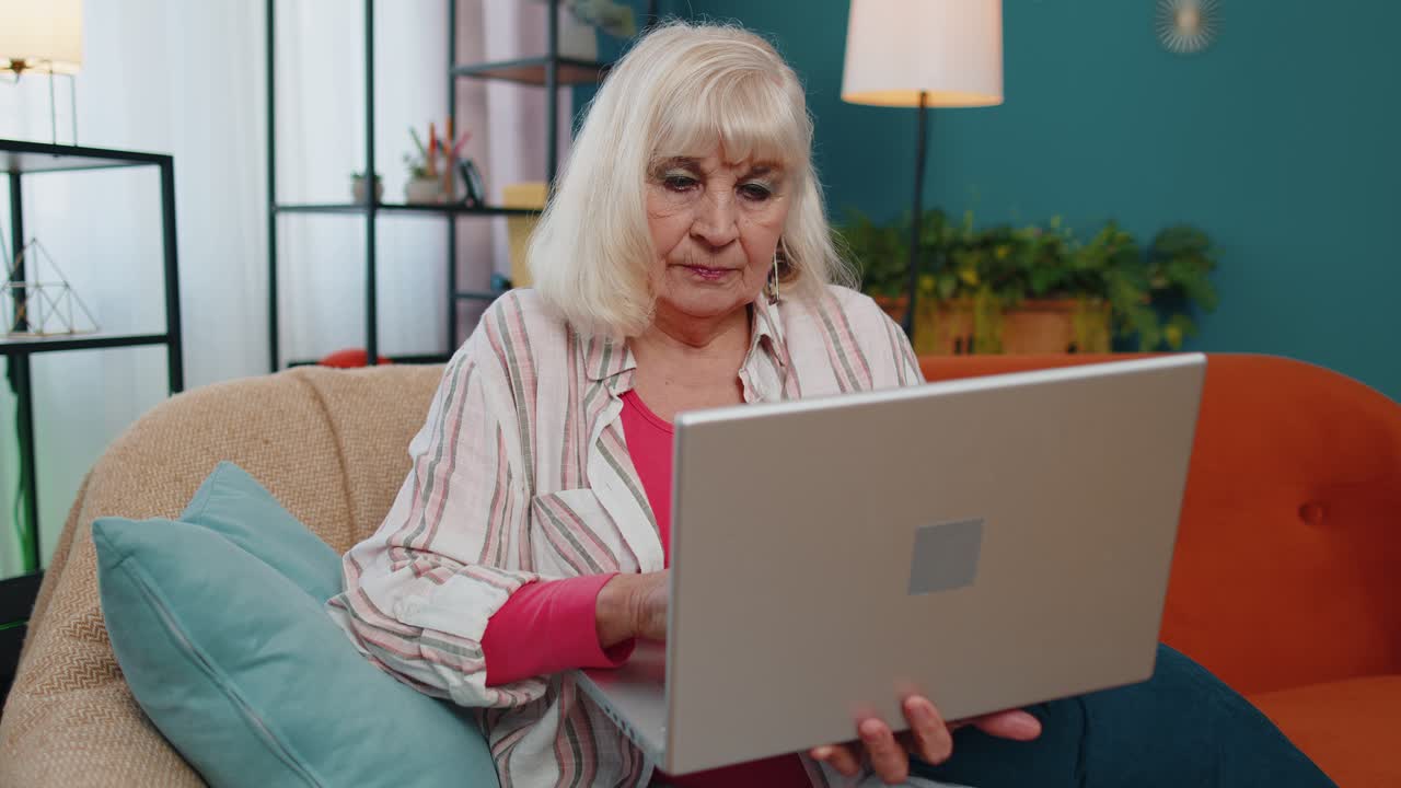 Senior old grandparent starts working on laptop sends messages makes online purchases at home