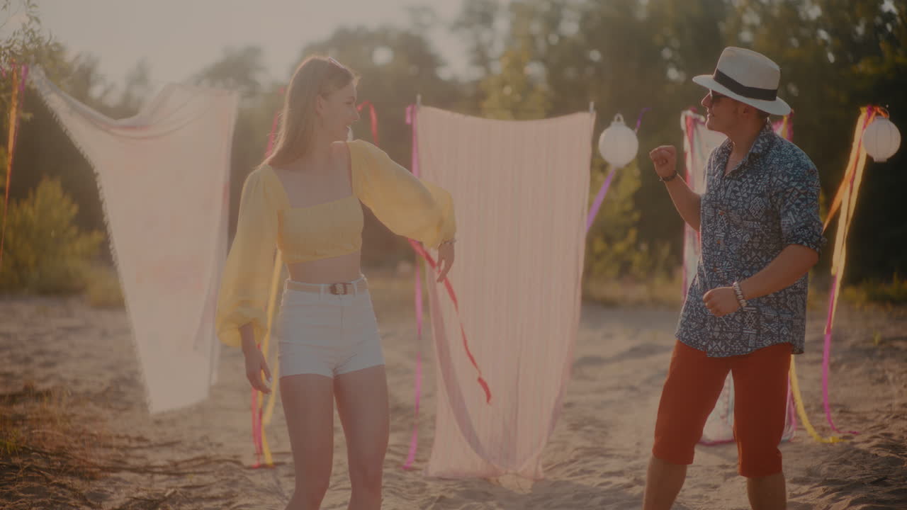 해변에 매달린 사롱에 맞서 춤을 추는 행복한 젊은 커플