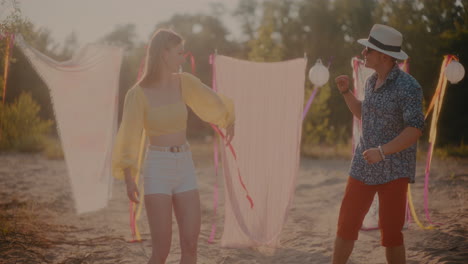 Happy-young-couple-dancing-against-sarongs-hanging-at-beach