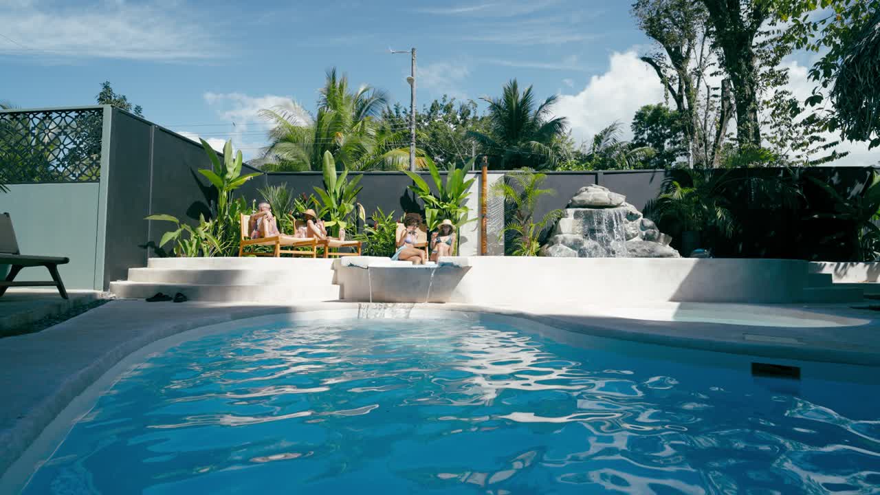 Group of Women Relaxing by a Tropical Swimming Pool on a Sunny Day