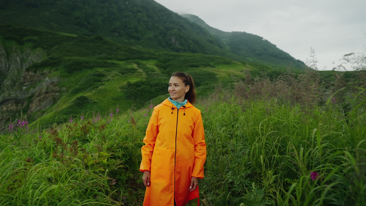 Woman Hiking in Mountains with Orange Raincoat