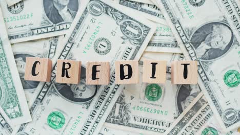 rotating word credit from wooden letters, on dollars, concept