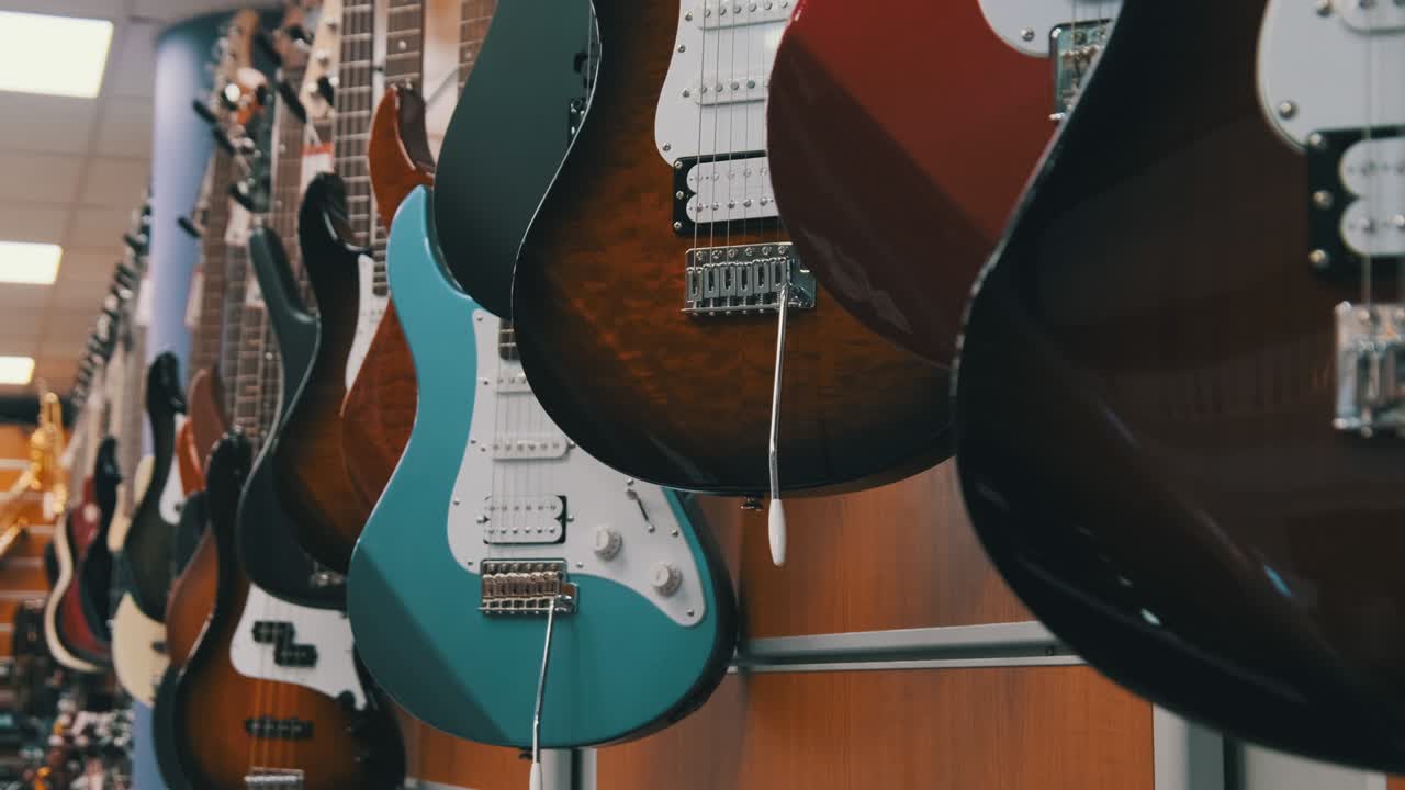 Gran cantidad de guitarras eléctricas multicolores colgadas en una tienda de música/guitarras