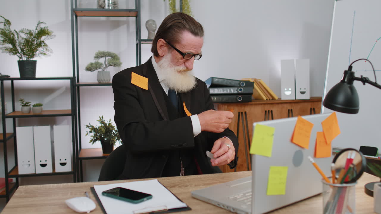 уставший, грустный, измученный бизнесмен, работающий на ноутбуке в офисе с множеством наклеек, паническая атака