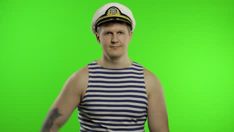 young sailor man salutes with hand to camera. seaman guy in sailor's vest