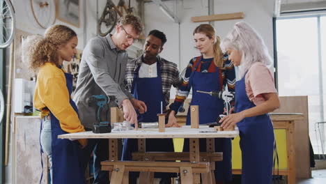 equipo multicultural de aprendices en el taller aprenden a ensamblar un marco de bicicleta construido a mano juntos