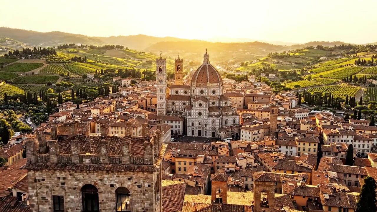 夕暮れ時のイタリアの都市の息をのむような空撮。豊かな緑のブドウ畑と絵のように美しい丘に囲まれ、田園の優雅さと歴史的建造物の真髄を捉えている。