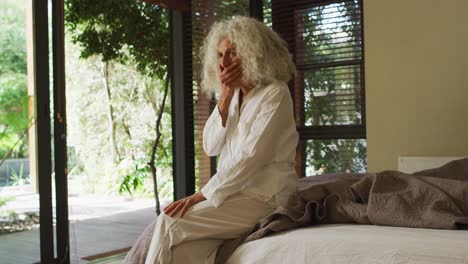 Thoughtful-caucasian-senior-woman-sitting-on-the-bed-at-home