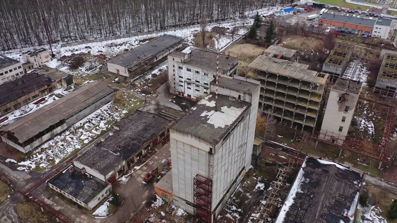 Aged factory with ruined buildings. Abandoned industry in dark background after the war. Aerial view. Orbital shot.