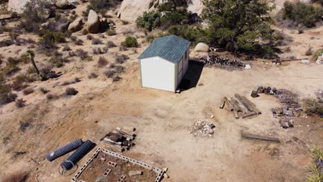 tiny shed surrounded by desert and huge boulders in aerial orbit view