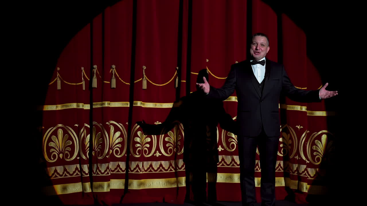 Senior man in costume on stage in darkness. Actor man in selective light on stage during the performance in the theater.
