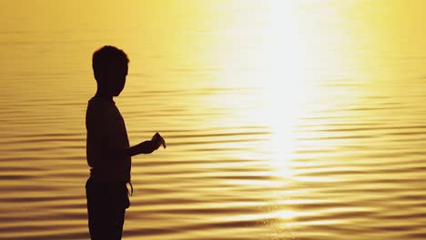 little boy holds a paper airplane in his hand at sunset. a child raised his hand up to sky and plays with origami in the evening in the street
