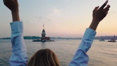beautiful girl enjoys sunset view of bosphorus with view of maiden tower at background in istanbul