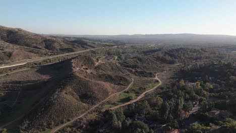 Expansive-View-of-Hill-with-Trails,-Busy-Freeway-in-the-Distance