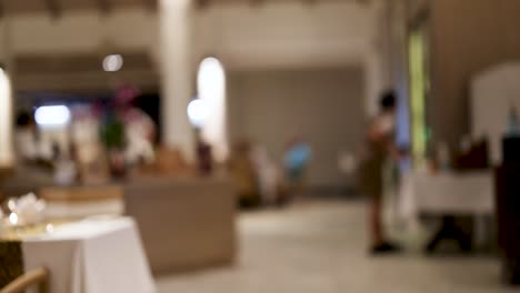 a bustling hotel restaurant with waitstaff moving efficiently, captured in a warm, blurred nighttime setting
