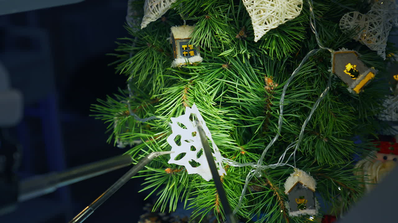 Christmas tree and metal cyborg arms. Robotic equipment for decorating New Year tree with paper snowflake. Intelligent machinery.
